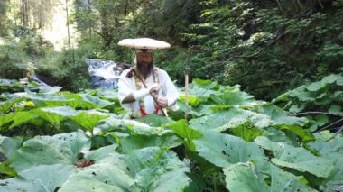 Sakallı Avrupalı bir adam geleneksel Japon Shugendo kıyafetiyle meditasyon yapıyor.