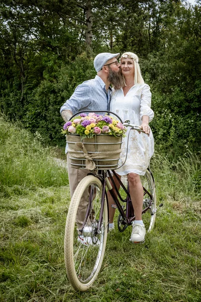 Beyaz Elbiseli Sarışın Kadın Kocası Bisiklet Süslemeli Çiçek Sepetiyle Poz — Stok fotoğraf