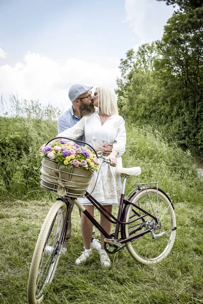 Beyaz Elbiseli Sarışın Kadın Kocası Bisiklet Süslemeli Çiçek Sepetiyle Poz — Stok fotoğraf