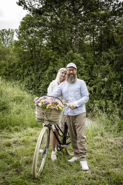 Blondynka Kobieta Białej Sukience Jej Mąż Pozowanie Rowerem Urządzone Kwiaty — Zdjęcie stockowe
