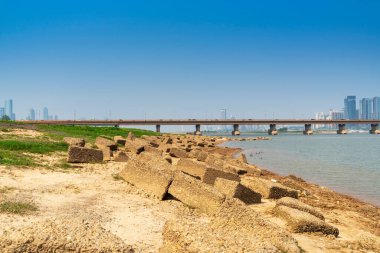 Sıcak, güneşli bir günde güzel, beyaz, kumlu bir plajın üzerinde modern, metropoliten bir şehir kulesinin uzun gökdelenleri..