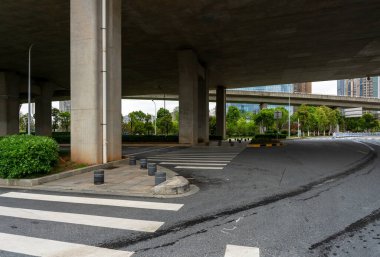 Şehirdeki üst geçidin altında beton yapı ve asfalt yol alanı