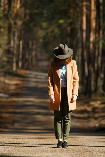 Chica en un sombrero se encuentra en el camino de los árboles del bosque — Foto de Stock