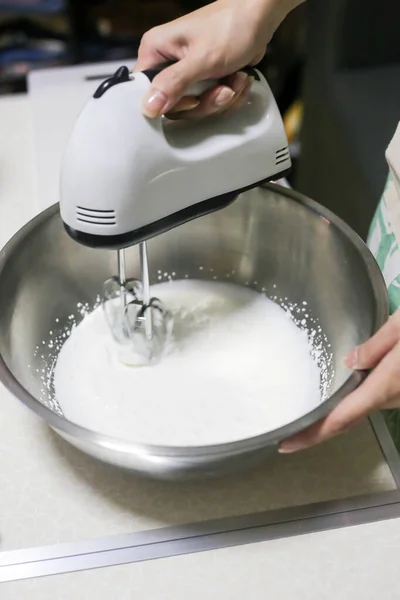 Whipped cream in bowl with electric hand mixers are used to make whipped cream