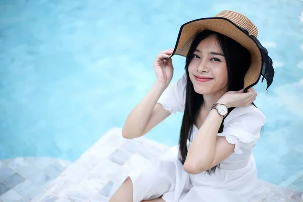 美丽的亚洲女人在豪华游泳池边消闲度暑假的观念 图库照片