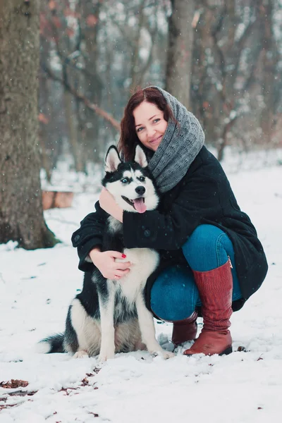 Mujer joven con perro husky en el parque de invierno — Foto de Stock