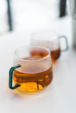 Mutfak masasında iki fincan çay var. Hafif hoş bir iç mekan. Masada bir buket lale var. Ev ve rahat atmosfer.