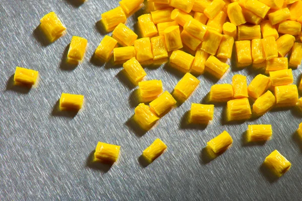 Yellow polymer pellets on stainless steel sheet — Stock Photo, Image