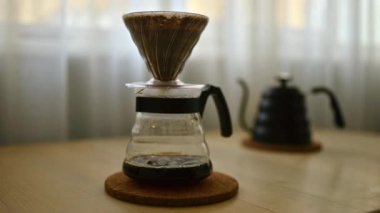 V60 filtreli taze kahve damlatılıyor. Kahve damlaları kağıt filtreden geçer. Kahve markaları, kafeler, kahve hocaları, içecek reklamları ve yaşam tarzı içeriği için mükemmel görüntüler..