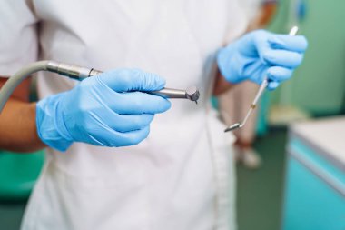 Tıbbi aletlerle dişçinin ellerini yakın plan çek. Büyük ayrıntı, dişçinin aynası, kıvrılma ve sonda. Diş sorunlarının çözümü kendinden emin, profesyonel jestlerle etkili.