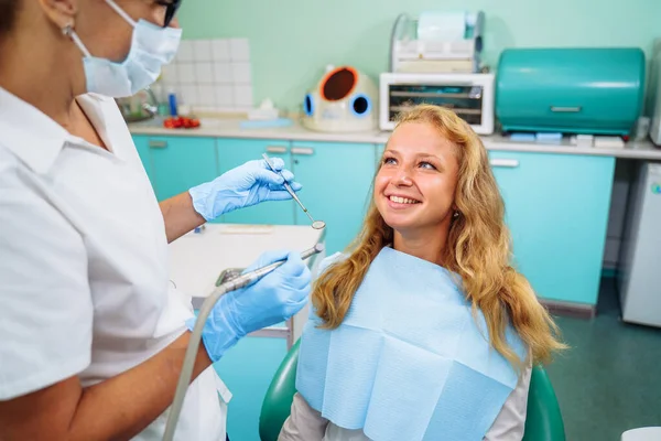 Cute european girl at the dentist\'s appointment. Close-up of a dentist\'s hands with medical instruments. Drill and tweezers in action. Selective focus. Dental care, taking care of teeth.