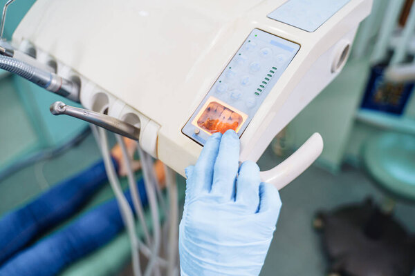 Крупный план деталей. Небольшое изображение зуба на устройстве с подсветкой лампы. Изучение проблемных участков зуба, нуждающихся в лечении. Поиск правильного лечения этого заболевания.