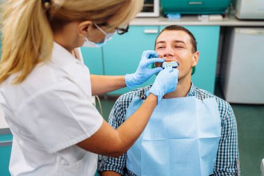 Özel bir plaka ve yumuşak malzemeyle üst diş kalıplarının kalıbını çıkarmak. Taç takmak için hazırlık. Modern bir klinikte dişçi prosedürleri. Ortodontik silikon çalıştırıcı.