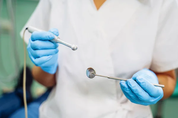 Close-up of the dentist\'s hands with medical devices. Large detail - dentist\'s mirror, curling and probe. Resolving dental problems effectively with confident, professional gestures.