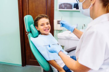 Diş muayenesi, dişçi ve asistanıyla çevrili güzel bir adama yapılıyor. Kadın dişçi muayenehanesinde hastayla konuşuyor ve tedaviye hazırlanıyor..