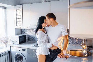 Çıplak, tutkulu bir öpüşme çifti. Adam ve kadın samimi seks yapıyor. Genç aşıkların erotik anları. Ateşli bebek sevgilisini nazikçe öpüyor, mutfak mobilyasına yaslanıyor. 14 Şubat 'ta..