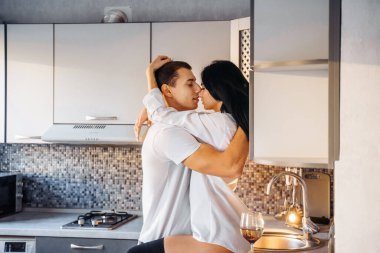 Çıplak, tutkulu bir öpüşme çifti. Adam ve kadın samimi seks yapıyor. Genç aşıkların erotik anları. Ateşli bebek sevgilisini nazikçe öpüyor, mutfak mobilyasına yaslanıyor. 14 Şubat 'ta..