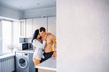 Çekici, tutkulu, yakışıklı bir kız ve mutfakta sevişen bir erkek. Çıplak kaslı gövdeli erkek arkadaşı beyaz gömlekli kadına nazikçe sarılıyor ve onu duvara bastırıyor..