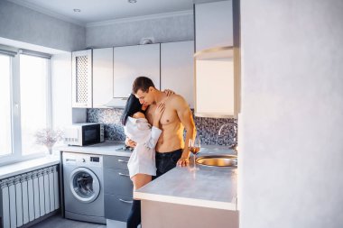 Çekici, tutkulu, yakışıklı bir kız ve mutfakta sevişen bir erkek. Çıplak kaslı gövdeli erkek arkadaşı beyaz gömlekli kadına nazikçe sarılıyor ve onu duvara bastırıyor..