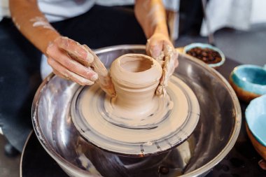 Sıcak, parlak bir atölyede çömlekçi tekeriyle çalışan bir kadın seramiğin elleri. Tecrübeli genç bir kadın ustaca bir kupa, vazo ya da tabak yapar. Yaratıcı insanlar, çömlek atölyesi.