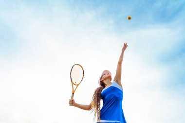 Tenis topu servisi. İyi bir atış için doğru duruş ve pratik hareketler gereklidir. Yetenekli bir tenisçi kadın yıllardır iyi eğitilmiş bir hareket sergiliyor. Top gökyüzünde..
