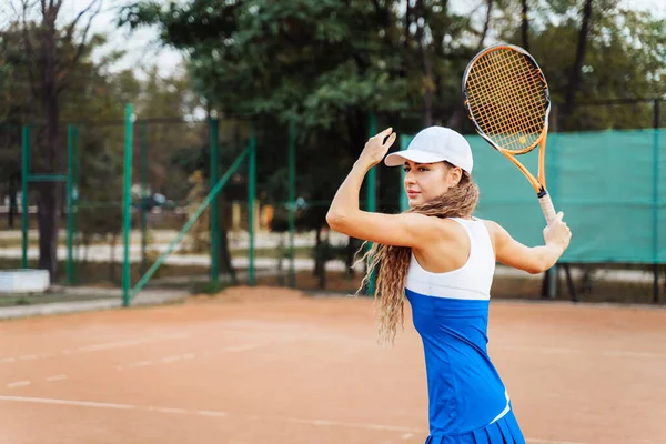 プロ装備の女性テニス選手がラケットでテニスボールを強く打つ お気に入りのワークアウトで楽しい時間を過ごす — ストック写真