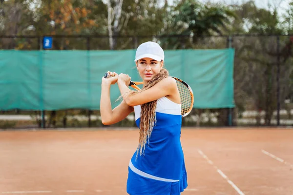 カメラを覗き込む 美しい ヨーロッパの女性は自信を持ってトレーニング中にテニスコートでボールを打つ 勝つことを決めた スタイリッシュなスポーツテニスの制服に身を包んだ ドレス — ストック写真