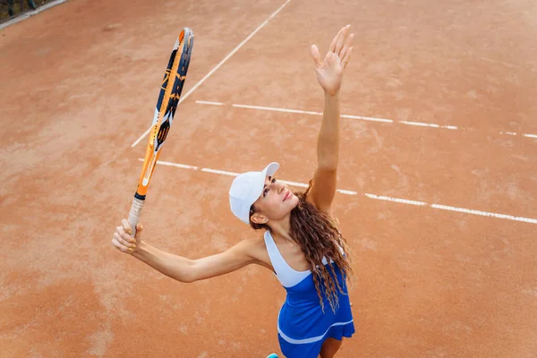 Tennis ball serving. Correct stance and practiced movements are essential for a good shot. A talented tennis player woman has been performing a well-trained movement for years. Ball up to the sky.
