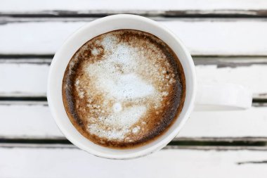 Beyaz seramik bir fincan kahveyi beyaz ahşap arka planda, üst manzarada kapat.. 