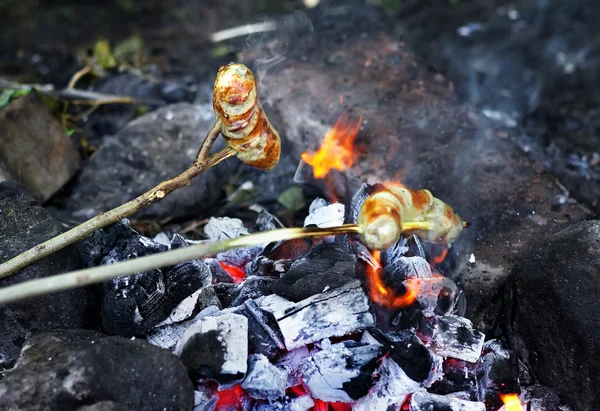 Сосиски на палочках горят на открытом огне — стоковое фото