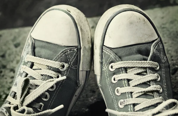 açık havada kirli gri spor ayakkabı, kot pantolon ayak.