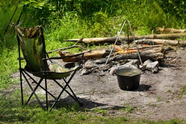 Relaxing and preparing food on campfire in camping clipart