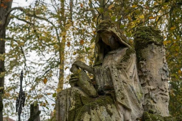 In an old cemetery there is a statue of a woman embedded in a marble top with some cobwebs.