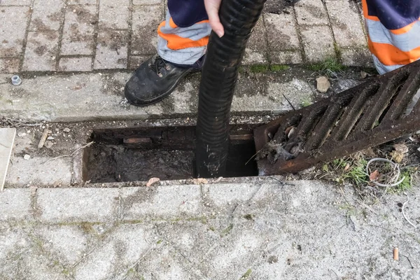 A clogged street drain is cleaned with the clearing service