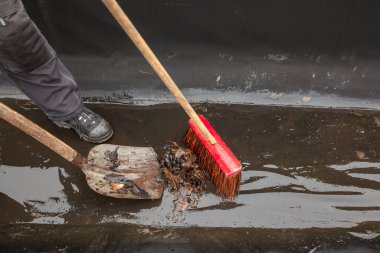 Düz bir çatının oluğu yapraklar ve dallar gibi ağaçların atıklarıyla doludur, Whit küreği, onu temizleyecektir.