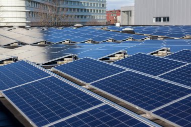 Konut alanındaki bir binada güneşli bir günde çatıda güneş panelleri var.