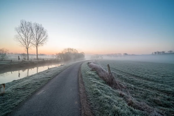 Early on a frosty morning with fog, this bike and footpath runs along the river