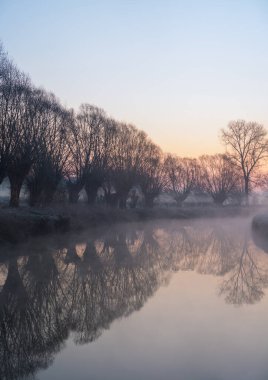 Sabahın erken saatlerinde sisli bir nehir boyunca yükselen birkaç virajlı