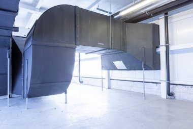 Büyük bir binanın bodrumundaki teknik bir odada uzun bir havalandırma borusu.