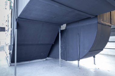 Büyük bir binanın bodrumundaki teknik bir odada uzun bir havalandırma borusu.