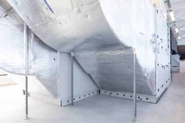 Büyük bir binanın bodrumundaki teknik bir odada uzun bir havalandırma borusu.