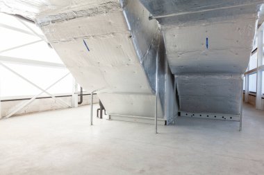 Büyük bir binanın bodrumundaki teknik bir odada uzun bir havalandırma borusu.