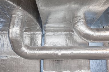 Büyük bir binanın bodrumundaki teknik bir odada uzun bir havalandırma borusu.