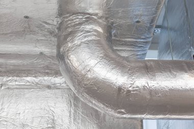 Büyük bir binanın bodrumundaki teknik bir odada uzun bir havalandırma borusu.