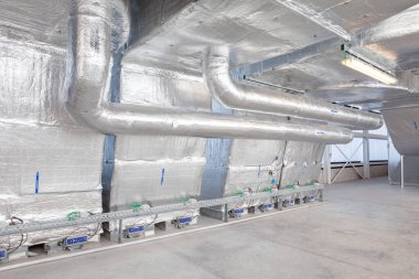 Büyük bir binanın bodrumundaki teknik bir odada uzun bir havalandırma borusu.