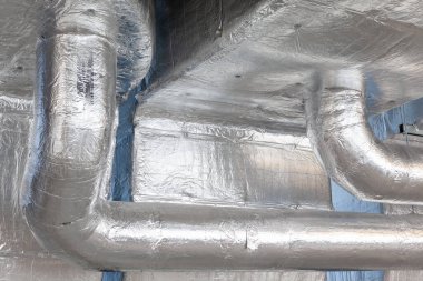 Büyük bir binanın bodrumundaki teknik bir odada uzun bir havalandırma borusu.