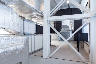 Büyük bir binanın bodrumundaki teknik bir odada uzun bir havalandırma borusu.