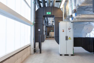 Büyük bir binanın bodrumundaki teknik bir odada uzun bir havalandırma borusu.