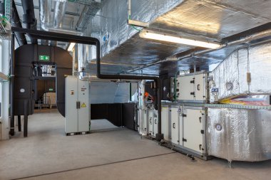 Büyük bir binanın bodrumundaki teknik bir odada uzun bir havalandırma borusu.