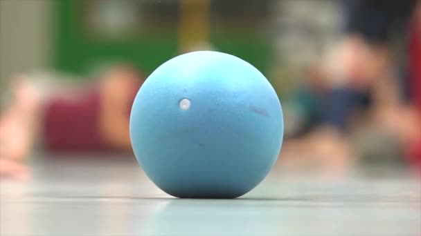 Der Ball rollt auf der Tanzfläche auf dem Hintergrund bewegter Füße. Impro-Tanz. — Stockvideo